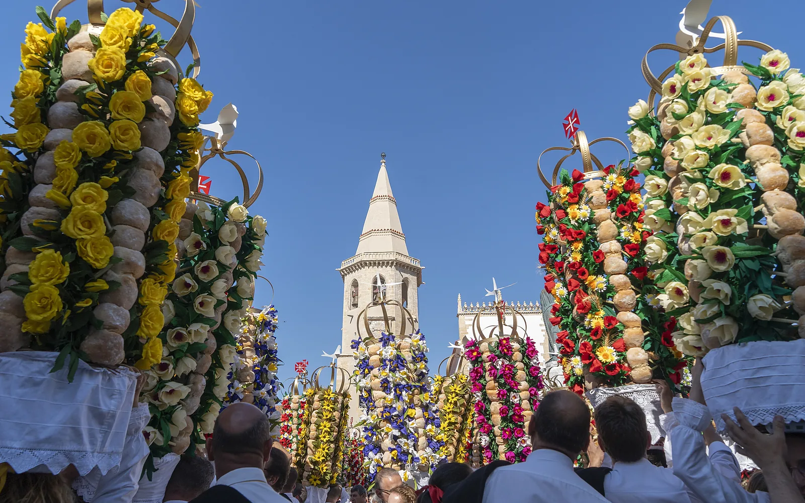 Des tabuleiros de pain et de fleurs en papier dressés au-dessus de la foule, à Tomar