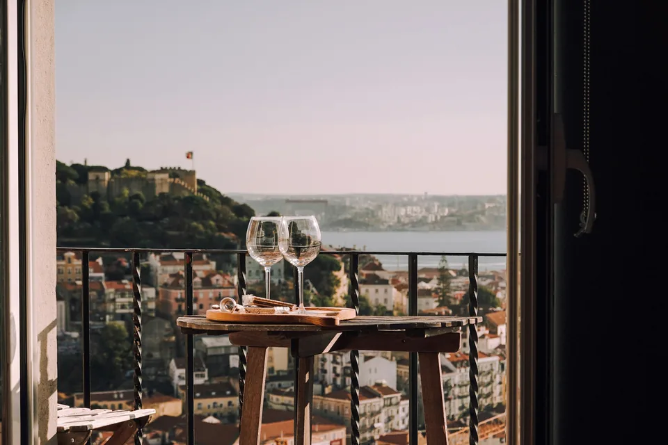 Dos copas de vino en un balcón frente al castillo de San Jorge, en Lisboa