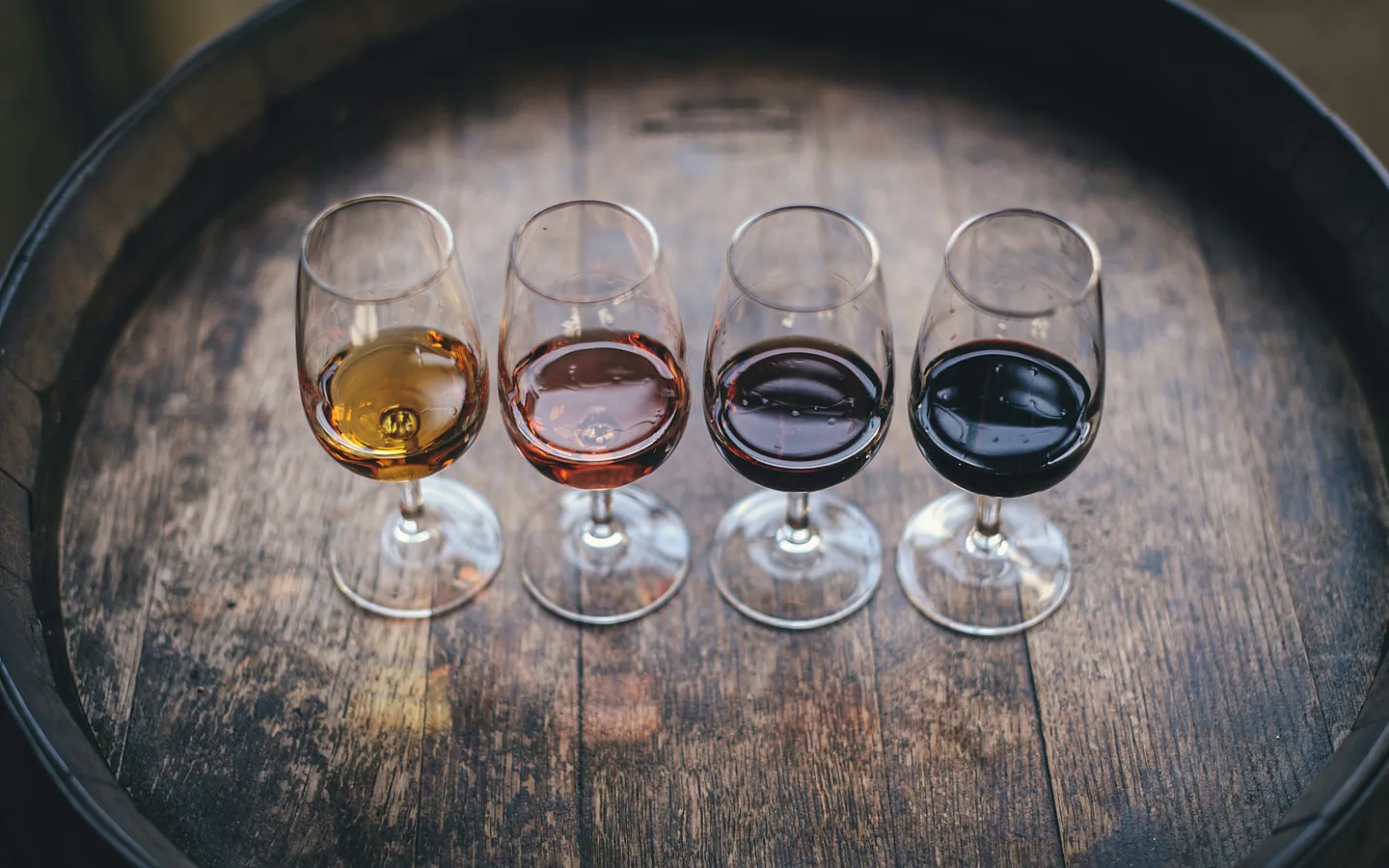 Cuatro vinos de Oporto sobre una barrica en una bodega de Vila Nova de Gaia