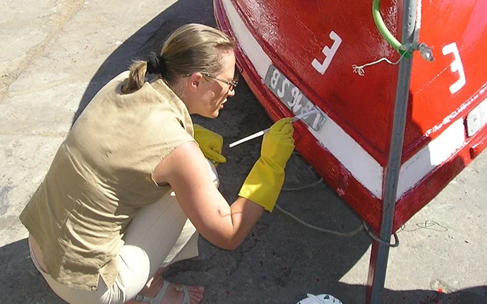 Un taller de pintura de barcos: una participante pinta una barca de pesca tradicional